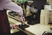 Mann presst Kaffee mit Stampfer in Portafilter in Café — Stockfoto