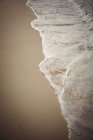 Primo piano del surf d'acqua di mare sulla sabbia della spiaggia — Foto stock