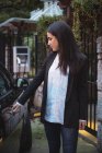 Schöne Frau öffnet Tür für Elektroautos an Ladestation für Elektrofahrzeuge — Stockfoto