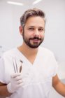 Дантист держит зубной пинцет и зеркало во рту в клинике — стоковое фото