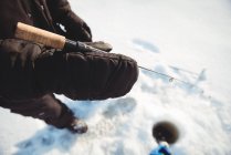 Mid section of ice fisherman holding fishing rod — Stock Photo