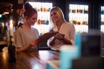 Офіціантка обговорює меню з жінкою в барі — стокове фото