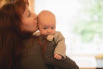 Крупним планом мати цілує новонароджену дитину вдома — стокове фото