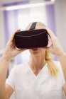 Médecin féminin portant un casque de réalité virtuelle en clinique — Photo de stock