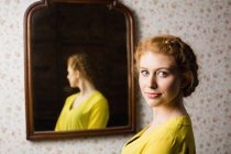 Retrato de uma bela mulher em pé na frente do espelho — Fotografia de Stock