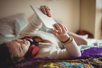 Женщина с цифровым планшетом во время кофе на кровати дома — стоковое фото