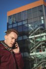 Мужчина говорит по мобильному телефону на улице перед офисным зданием — стоковое фото
