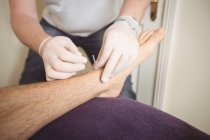 Close-up de fisioterapeuta realizando agulhas secas na perna de um paciente na clínica — Fotografia de Stock