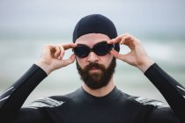 Athlete in wet suit wearing swimming goggles on beach — Stock Photo