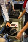 Бизнесмен кладет вещи в лоток для проверки безопасности в терминале аэропорта — стоковое фото