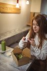 Женщина фотографирует салат на мобильный телефон в ресторане — стоковое фото