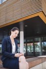 Geschäftsfrau sitzt vor Bürogebäude und benutzt Handy — Stockfoto