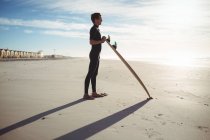 Nachdenklicher Surfer steht mit Surfbrett am Strand — Stockfoto