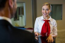 Female staff giving boarding pass to the businessman at the check in desk — Stock Photo