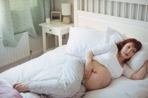 Mujer embarazada pensativo relajarse en la cama en el dormitorio - foto de stock