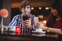 Couple utilisant des téléphones mobiles dans le restaurant — Photo de stock