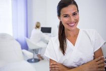 Портрет усміхнений стоматолога, стоячи з руки перетнув клініки — стокове фото