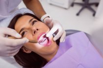 Закри стоматолога, вивчаючи жіночий пацієнтів зубів з рота дзеркало — Stock Photo