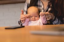 Sección media de la madre jugando con el bebé en casa - foto de stock