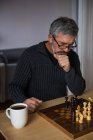 Homme attentif jouant aux échecs à la maison — Photo de stock