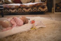 Милый ребенок лежит на ковре в гостиной дома — стоковое фото