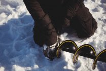 Mid section of ice fisherman placing ice screws in the snow — Stock Photo
