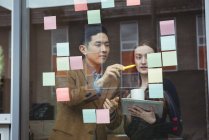 Business executives discussing over sticky notes in office — Stock Photo