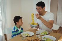 Padre che serve cibo a suo figlio sul tavolo da pranzo a casa — Foto stock