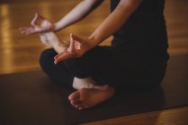 Cropped view of practicing woman doing mudra on yoga mat in fitness studio — Stock Photo