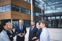 Group of businesspeople interacting outside office building — Stock Photo