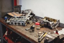 Établi avec des pièces de voiture et des outils dans garage de réparation — Photo de stock
