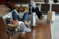 Бизнесмен лежит на стульях и отдыхает в зоне ожидания в терминале аэропорта — стоковое фото
