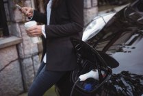 Женщина с мобильного телефона во время зарядки электромобиля на электростанции зарядки автомобиля — стоковое фото