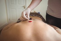 Nahaufnahme des Physiotherapeuten bei der Durchführung elektrotrockener Nadelstiche auf dem Rücken eines Patienten in der Klinik — Stockfoto