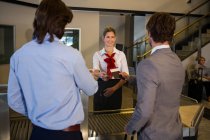 Il personale femminile controlla la carta d'imbarco dei passeggeri al banco del check-in in aeroporto — Foto stock