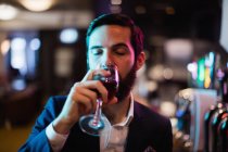 Uomo d'affari che beve un bicchiere di vino al bar — Foto stock