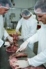 Чоловічі м'ясники ріжуть м'ясо на м'ясному заводі — стокове фото