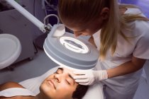 Жінка-лікар, яка вивчає чоловіче обличчя для косметичного лікування в клініці — стокове фото