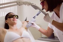 Medico che esegue la depilazione laser sulla pelle giovane paziente in clinica — Foto stock