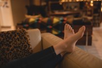 Дівчина розслабляється на дивані у вітальні вдома, обрізана — стокове фото