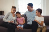 Sorrindo pais e crianças usando tablet digital na sala de estar — Fotografia de Stock