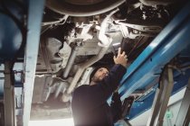 Механічне вивчення автомобіля з ліхтариком у ремонті гаража — стокове фото