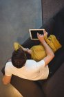 Весела пара лежить разом на дивані, використовуючи цифровий планшет у вітальні — стокове фото