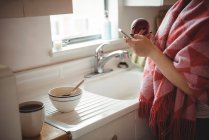 Розділ середині жінці за допомогою мобільного телефону під час проведення apple кухні в домашніх умовах — стокове фото