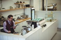 Nachdenklicher Mann blickt auf Klemmbrett im Café — Stockfoto