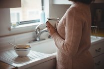 Середина жінки тримає чашку кави на кухні — стокове фото