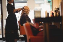 Женщина парикмахер укладки клиентов волосы в салоне — стоковое фото