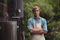 Портрет впевненого чоловіка в фартусі, що стоїть на домашній пивоварні — стокове фото