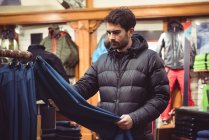 Uomo che seleziona abbigliamento in un negozio di abbigliamento — Foto stock