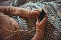 Frau sitzt zu Hause auf Sofa und hört Musik mit Handy im Wohnzimmer — Stockfoto